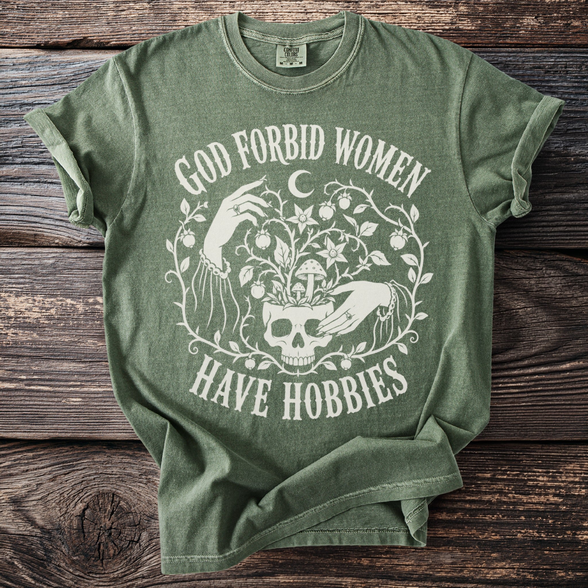 Green t-shirt with white text and graphics about women having hobbies.