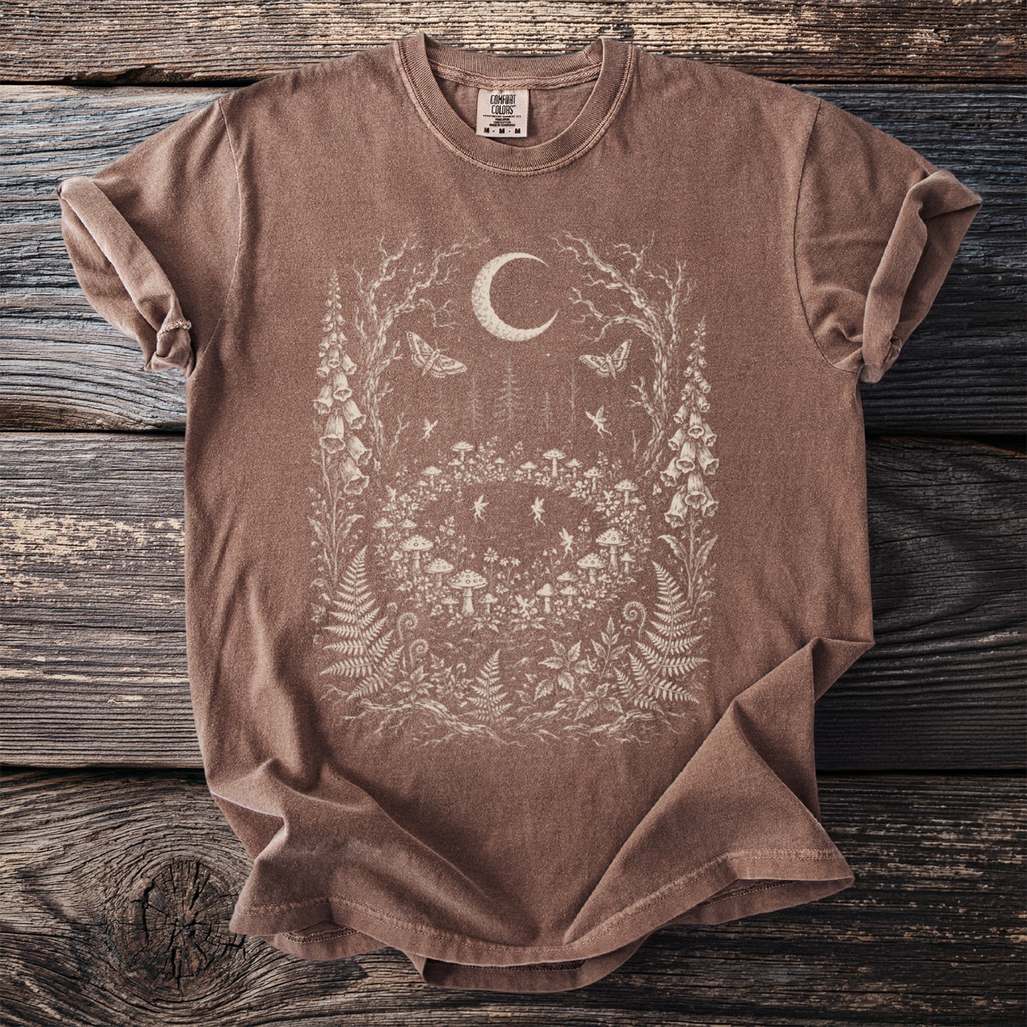 Brown t-shirt with a fairy forest, mushrooms, and moon graphic.