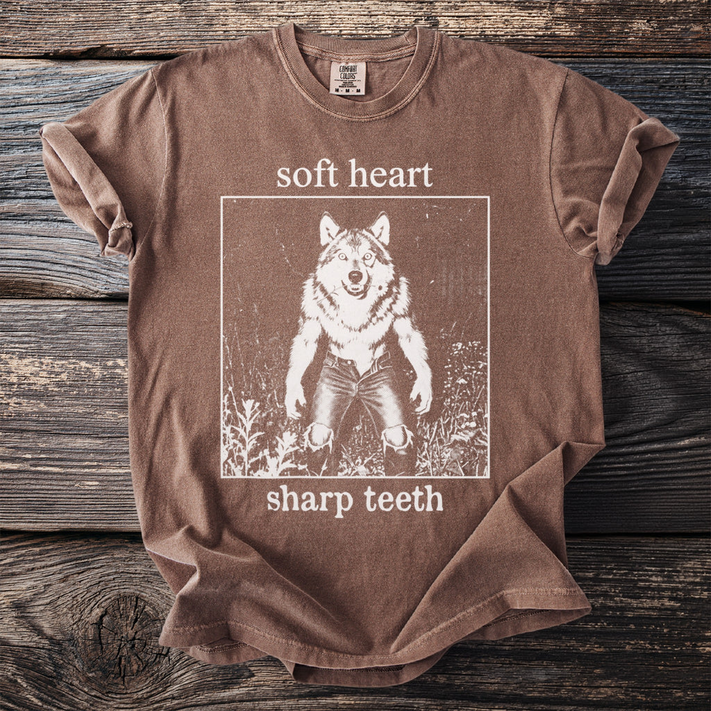 Brown t-shirt with white graphic of a werewolf and text "soft heart sharp teeth".