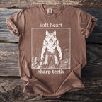 Brown t-shirt with white graphic of a werewolf and text "soft heart sharp teeth".