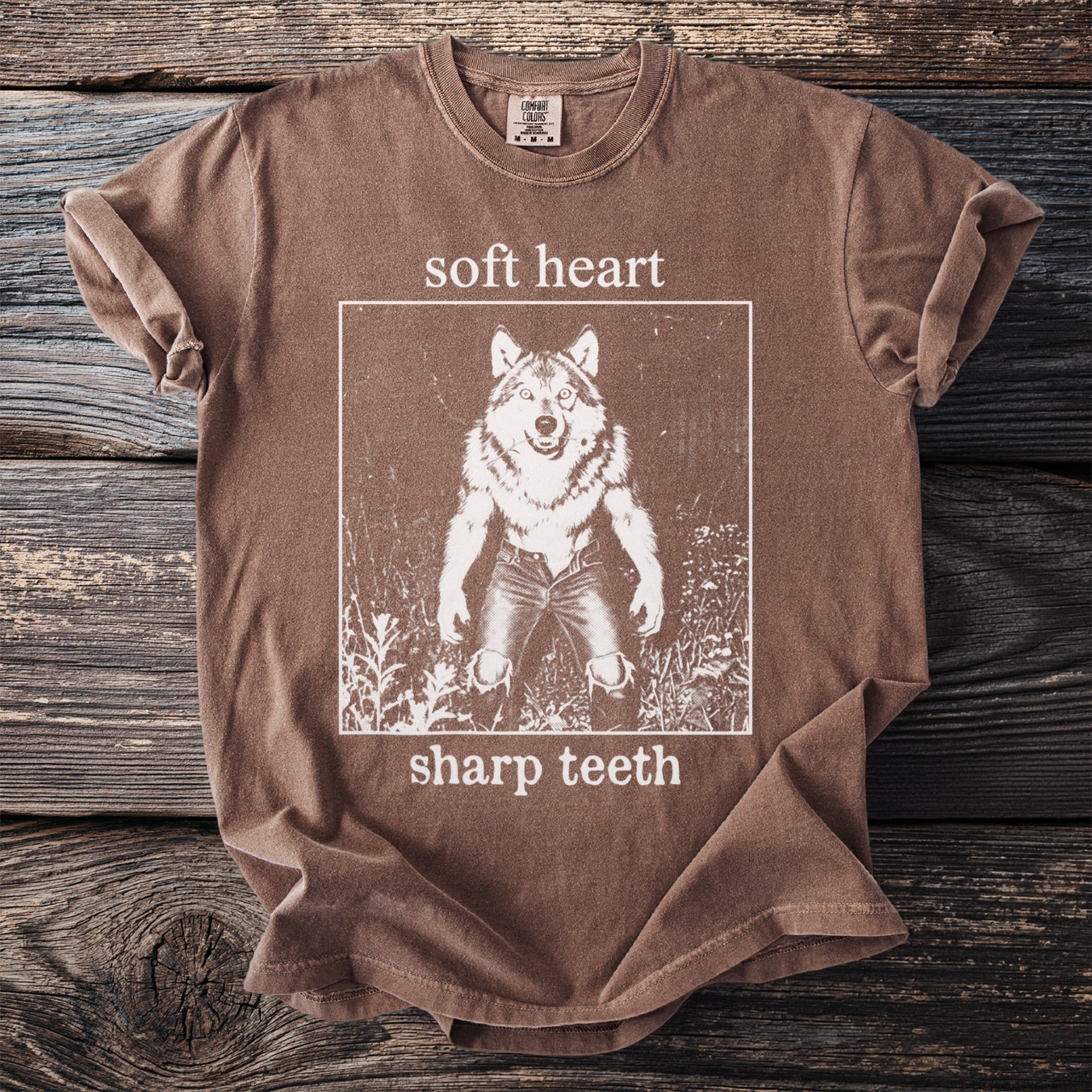 Brown t-shirt with white graphic of a werewolf and text "soft heart sharp teeth".