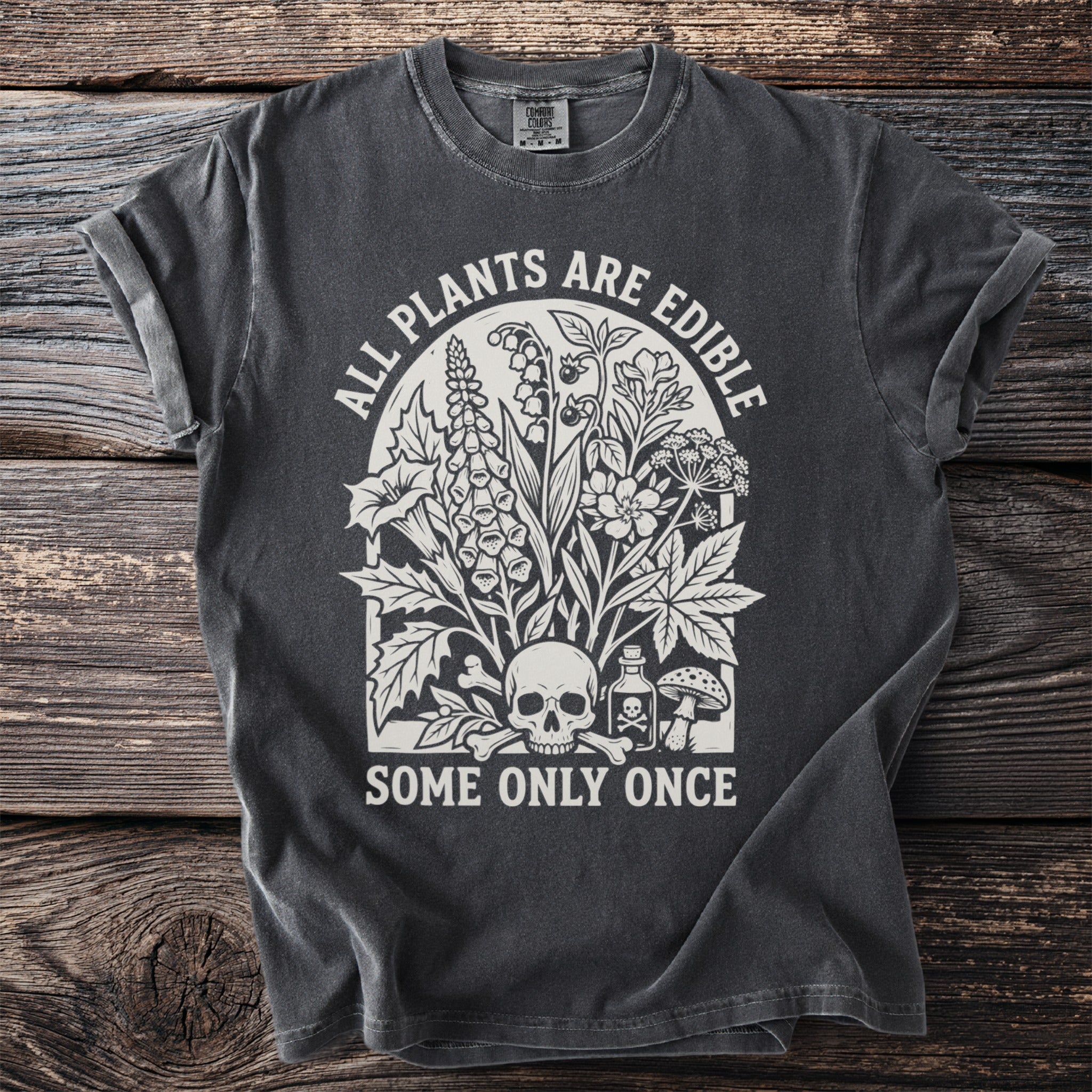Dark grey t-shirt with white text "ALL PLANTS ARE EDIBLE SOME ONLY ONCE" and floral skull graphic.