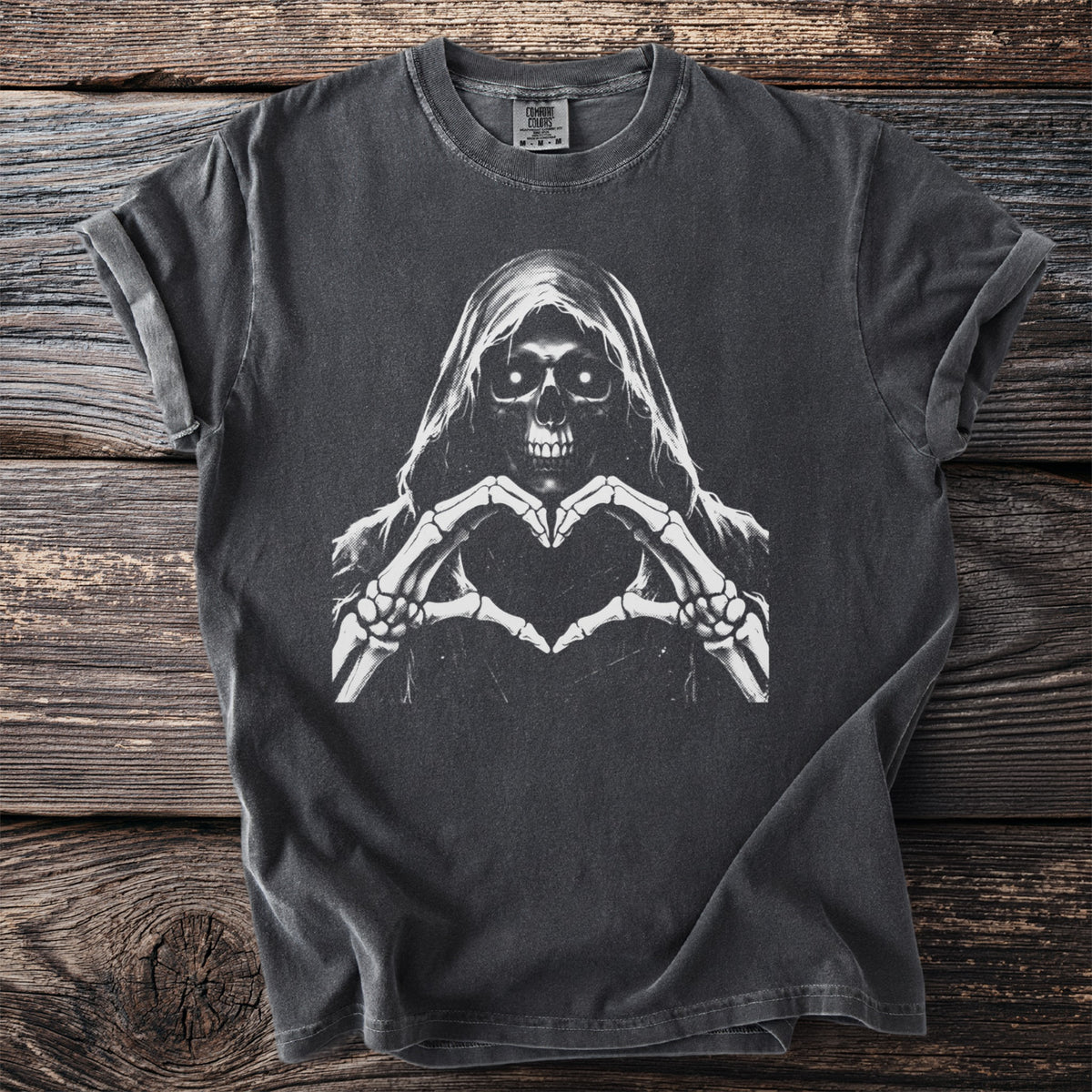 Dark t-shirt with grim reaper making heart shape with skeleton hands graphic.
