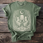 Green t-shirt with occult figures, campfire, moon, and nature elements design.