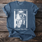 Blue t-shirt with text "it's not the moon i'm just like this" and a graphic.