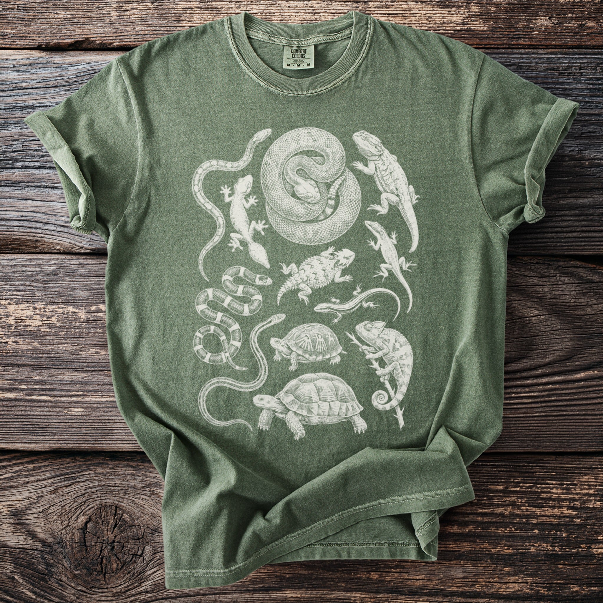 Green t-shirt with charcoal sketch-style print of various reptiles and amphibians.
