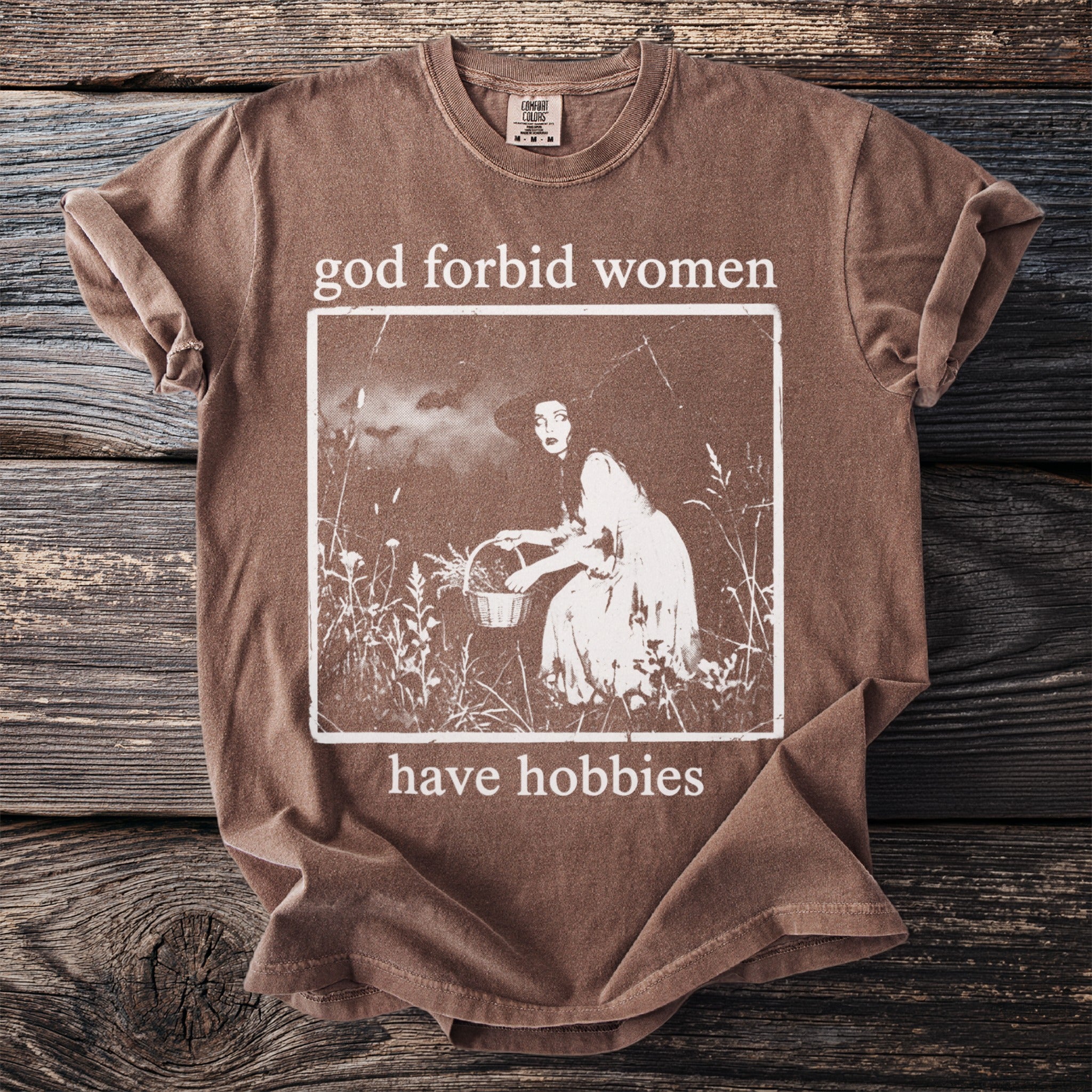 Brown t-shirt with "god forbid women have hobbies" and vintage image.