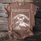 Brown t-shirt with a graphic of a cat peeking from under a blanket and "do not perceive me" text.