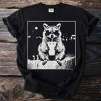 Black t-shirt with a white graphic of a raccoon wearing sunglasses, drinking from a cup.