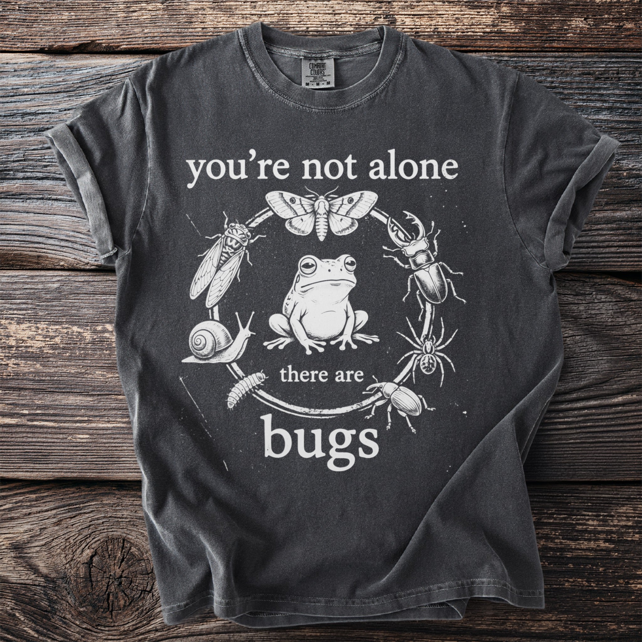 Dark grey t-shirt with "you're not alone there are bugs" and illustrated frog and insects.