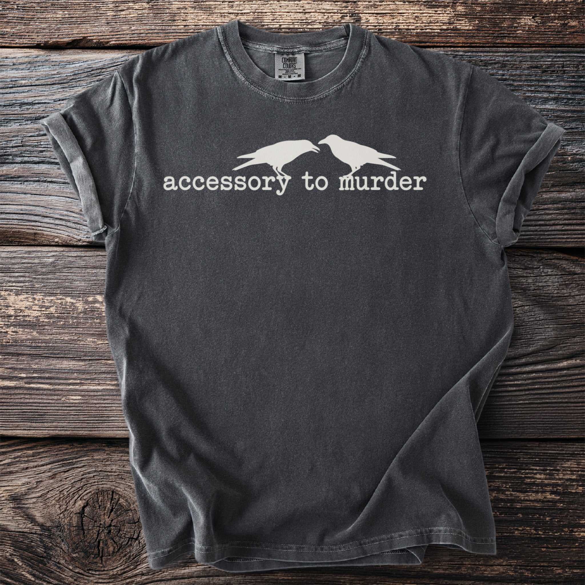 Dark t-shirt with white text "accessory to murder" and two birds.
