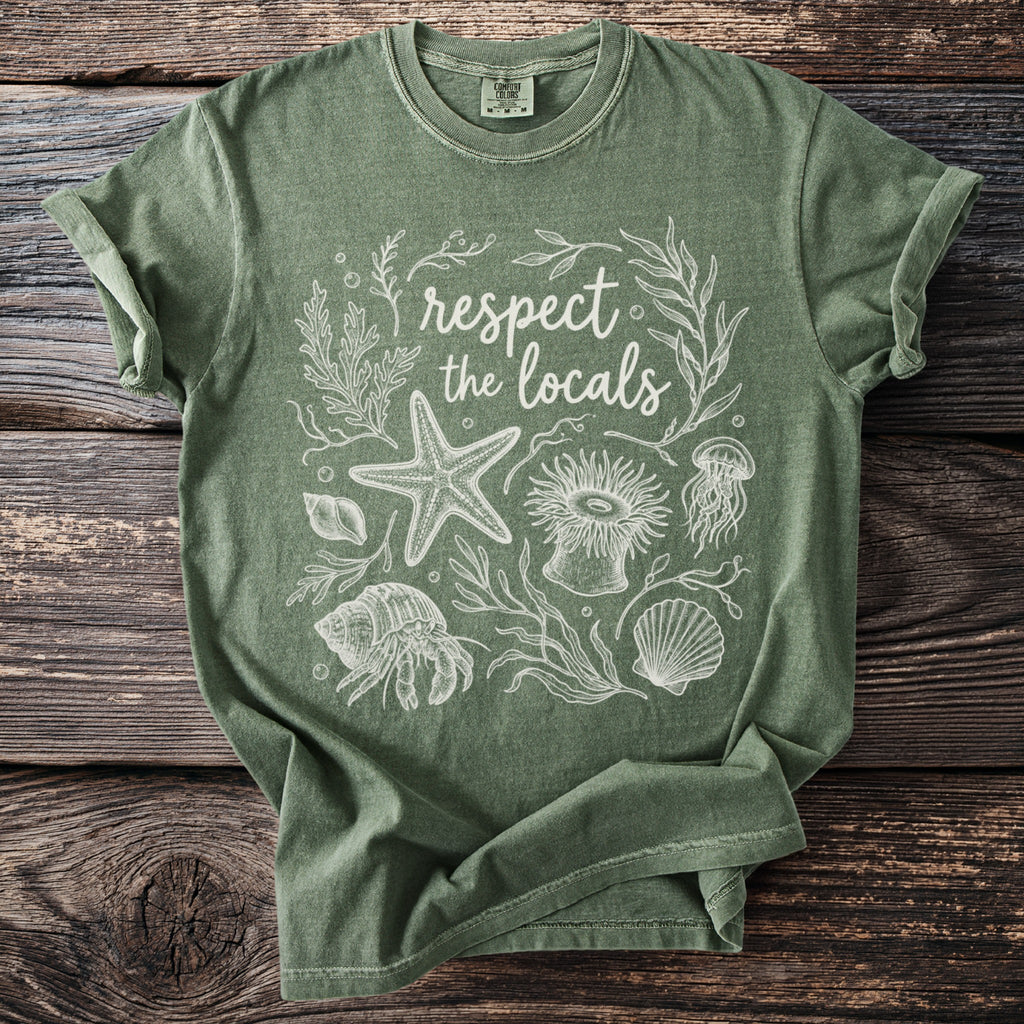 Green t-shirt with white line art of sea creatures and "respect the locals" text.