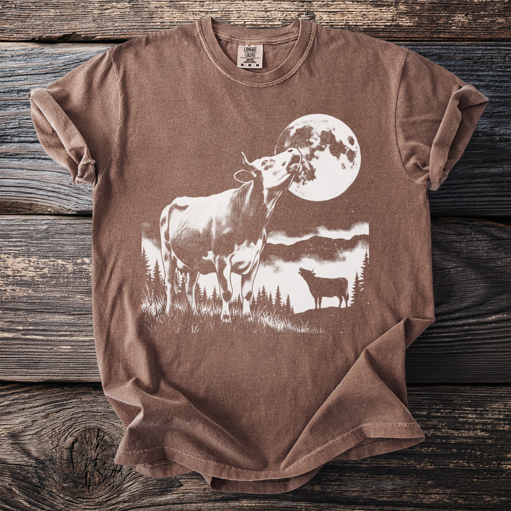 Brown t-shirt with white graphic of a cow mooing at the moon and another cow.