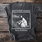 dark t-shirt with text "god forbid women have hobbies" and witchy graphic