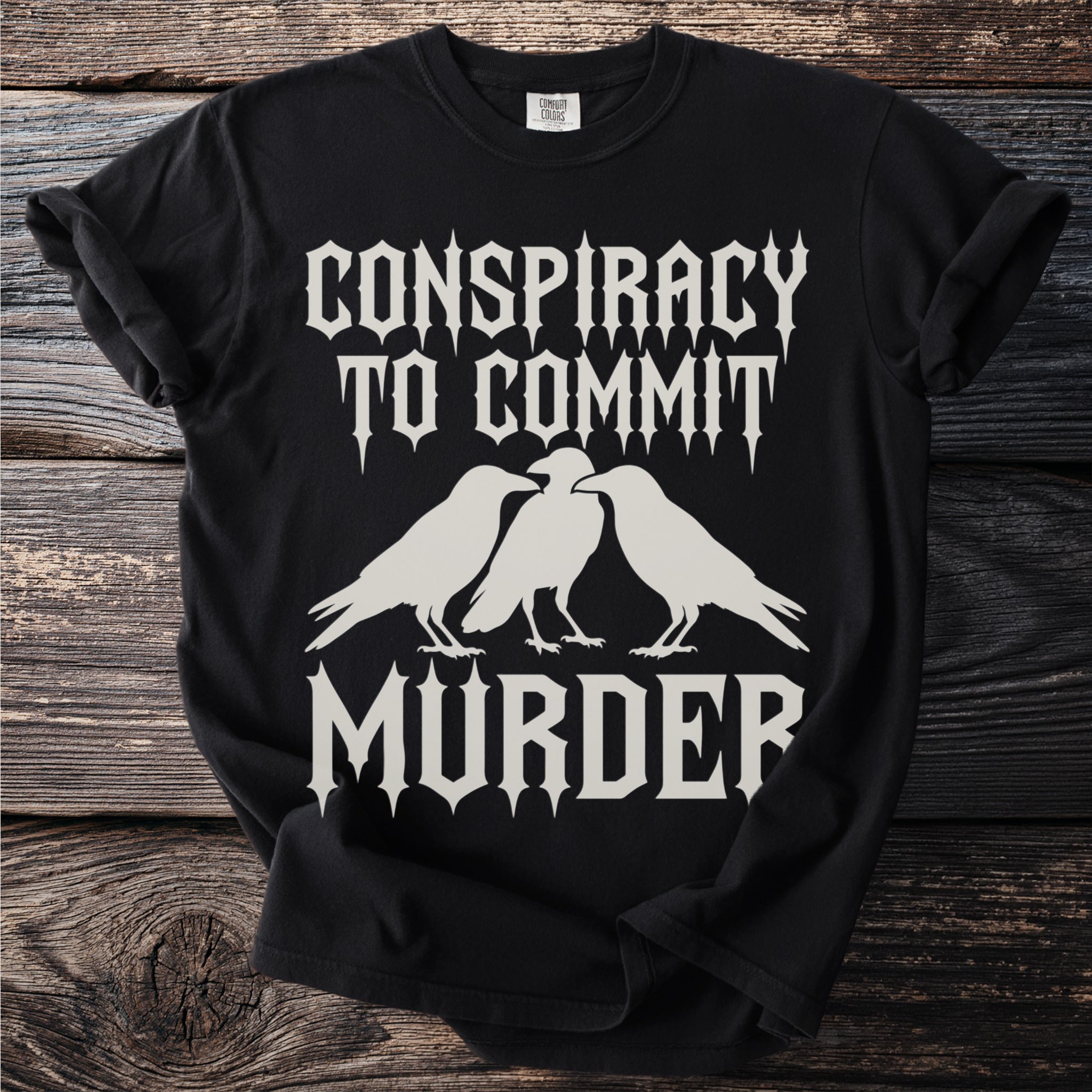 Black t-shirt with "Conspiracy to Commit Murder" text and ravens graphic.