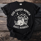 Black t-shirt with a white graphic and text: "GOD FORBID WOMEN HAVE HOBBIES".