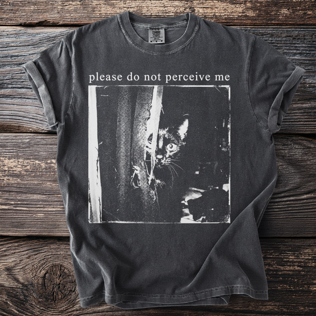 Charcoal t-shirt with a black and white image of a cat peeking from behind fabric and text "please do not perceive me".