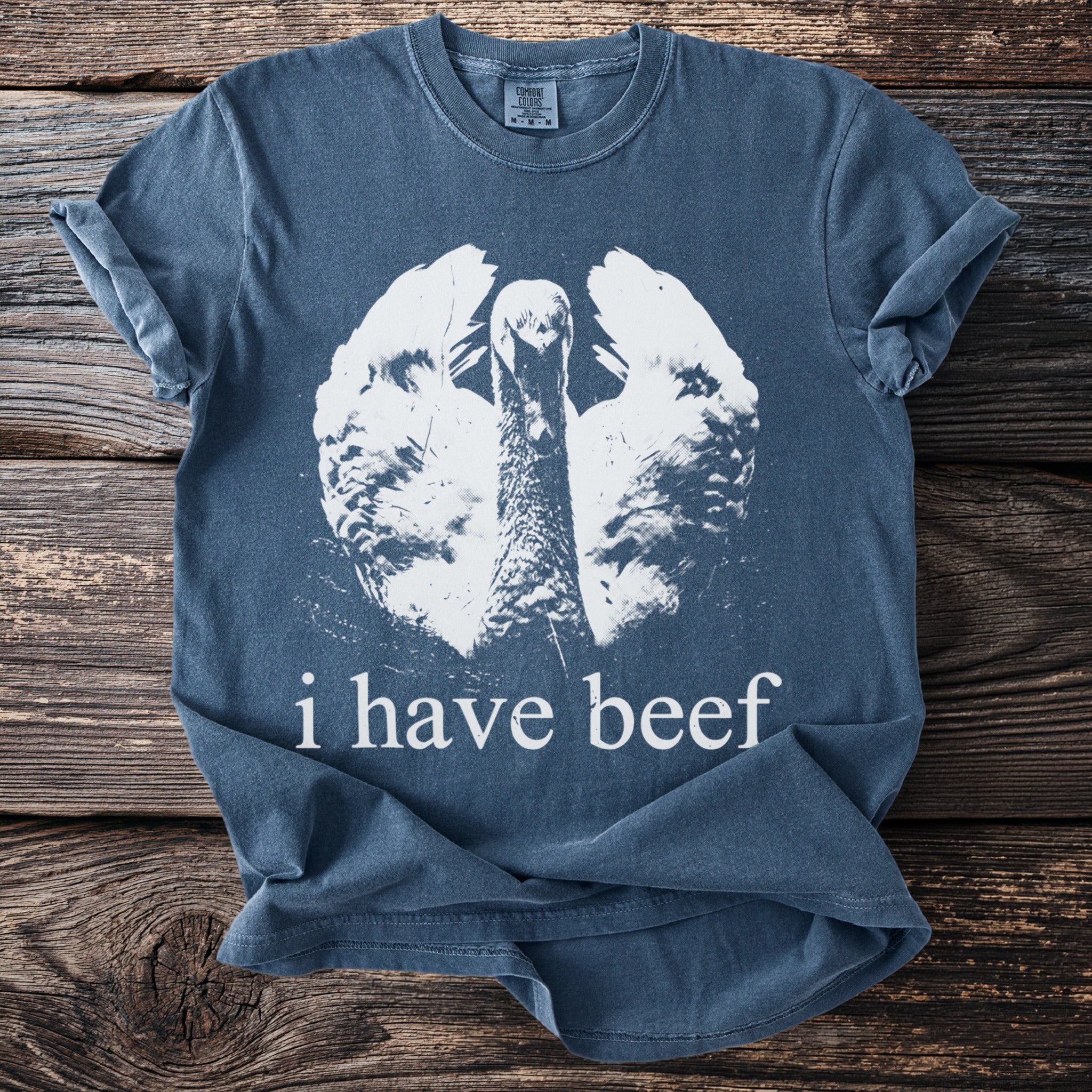 Blue t-shirt with a white graphic of a turkey and text "i have beef".