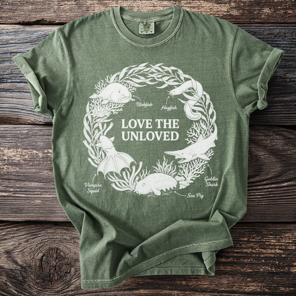 T-shirt graphic features a wreath of marine life and text "LOVE THE UNLOVED."