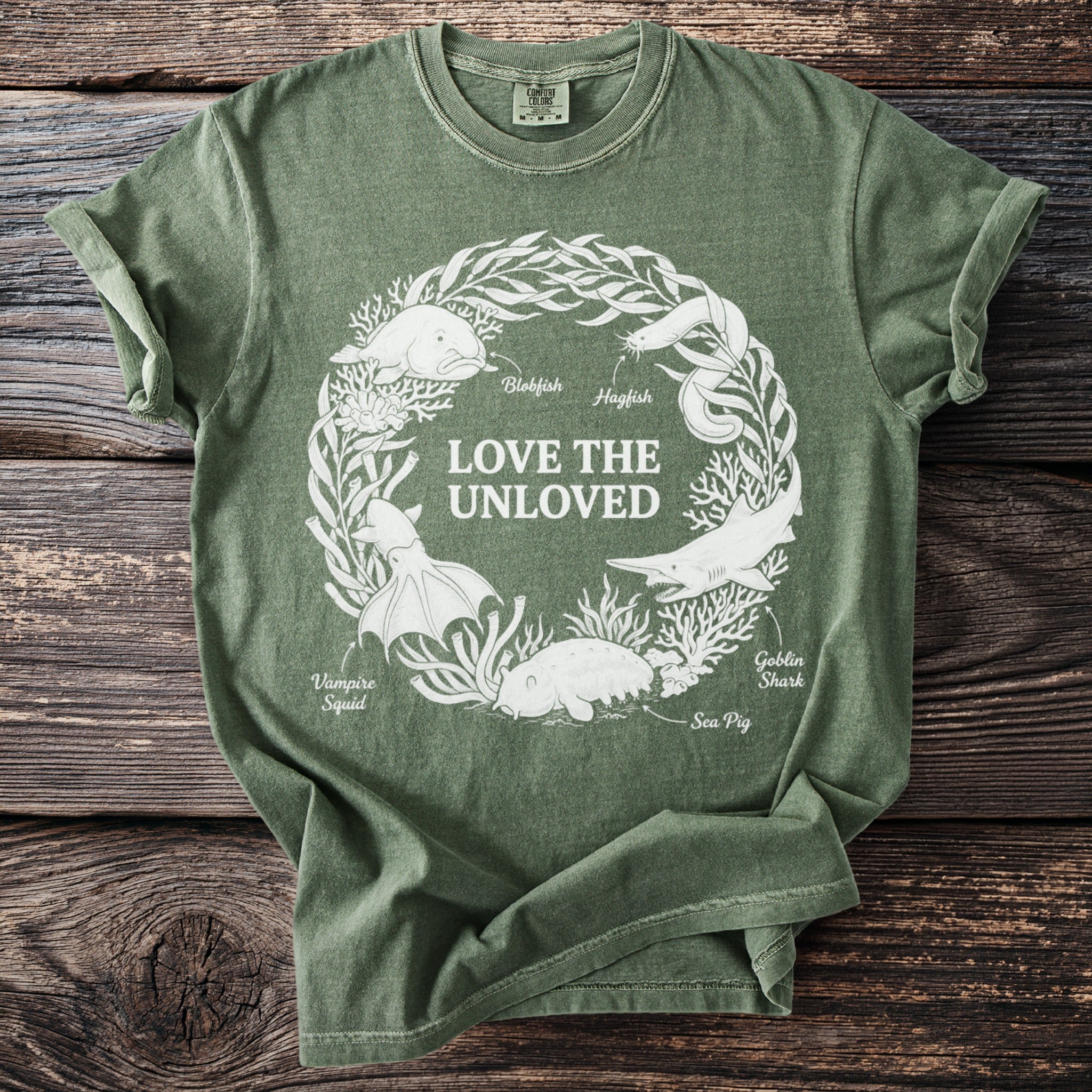 T-shirt graphic features a wreath of marine life and text "LOVE THE UNLOVED."