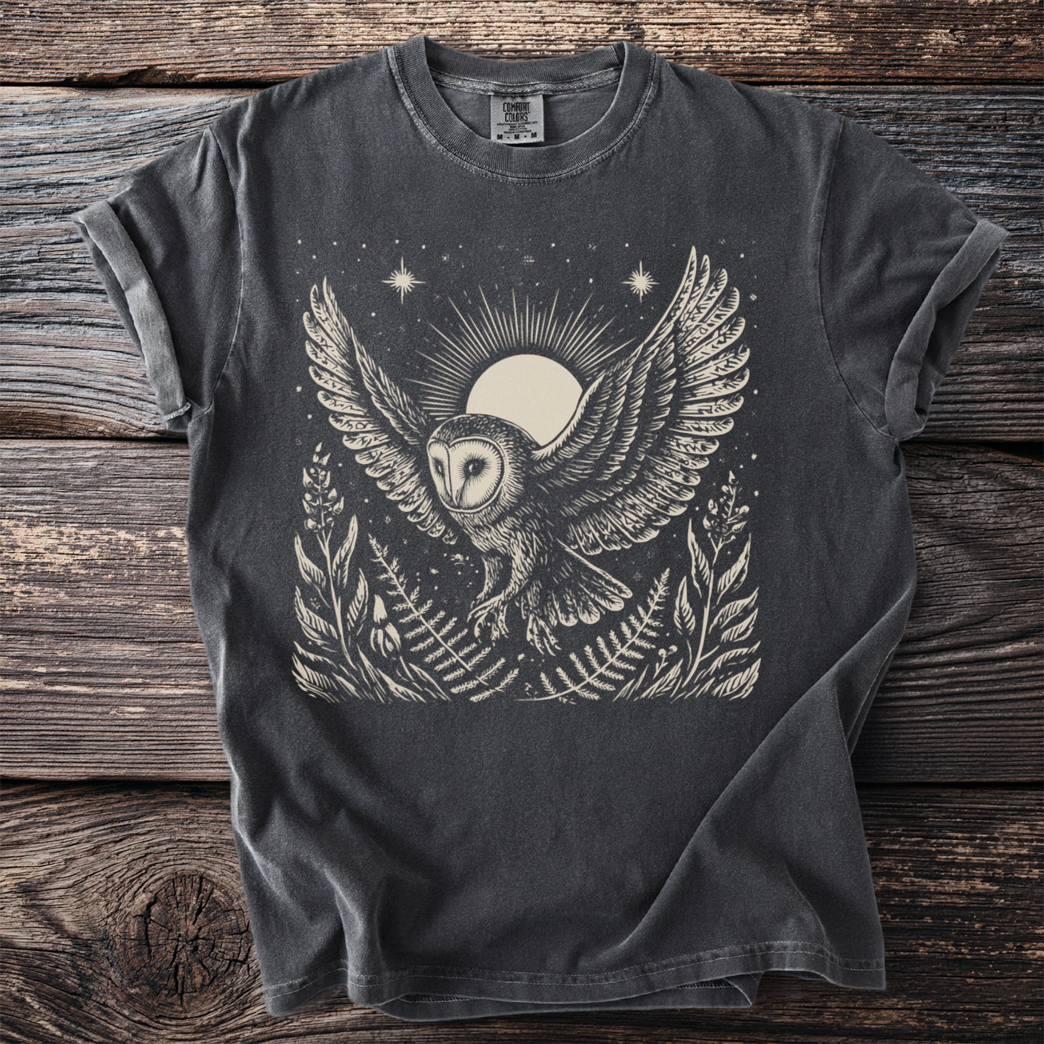 Barn owl with wings spread on a dark t-shirt with moon and foliage design.