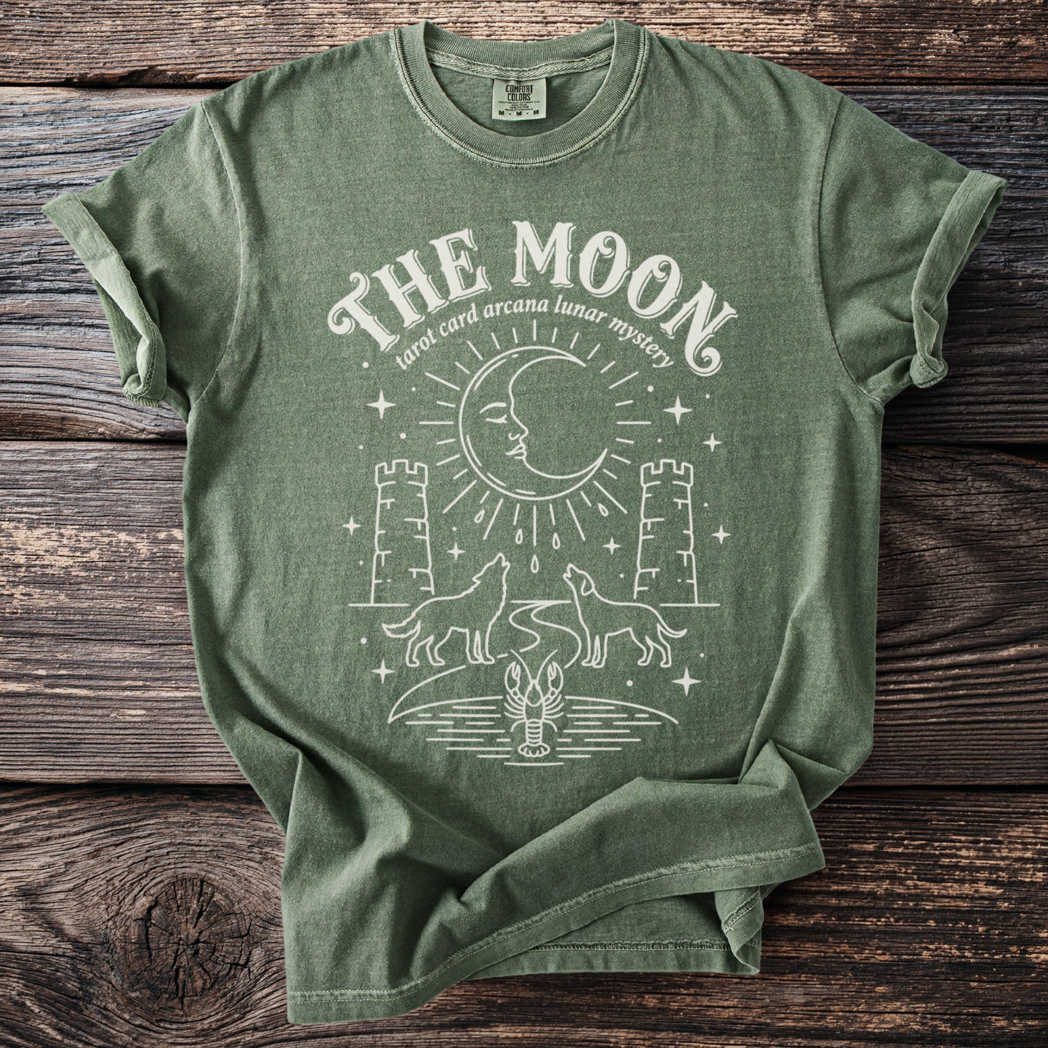 Green t-shirt with white graphic of moon, wolves, towers, and lobster.