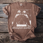 Brown t-shirt with white graphic of two birds and the text "attempted murder".