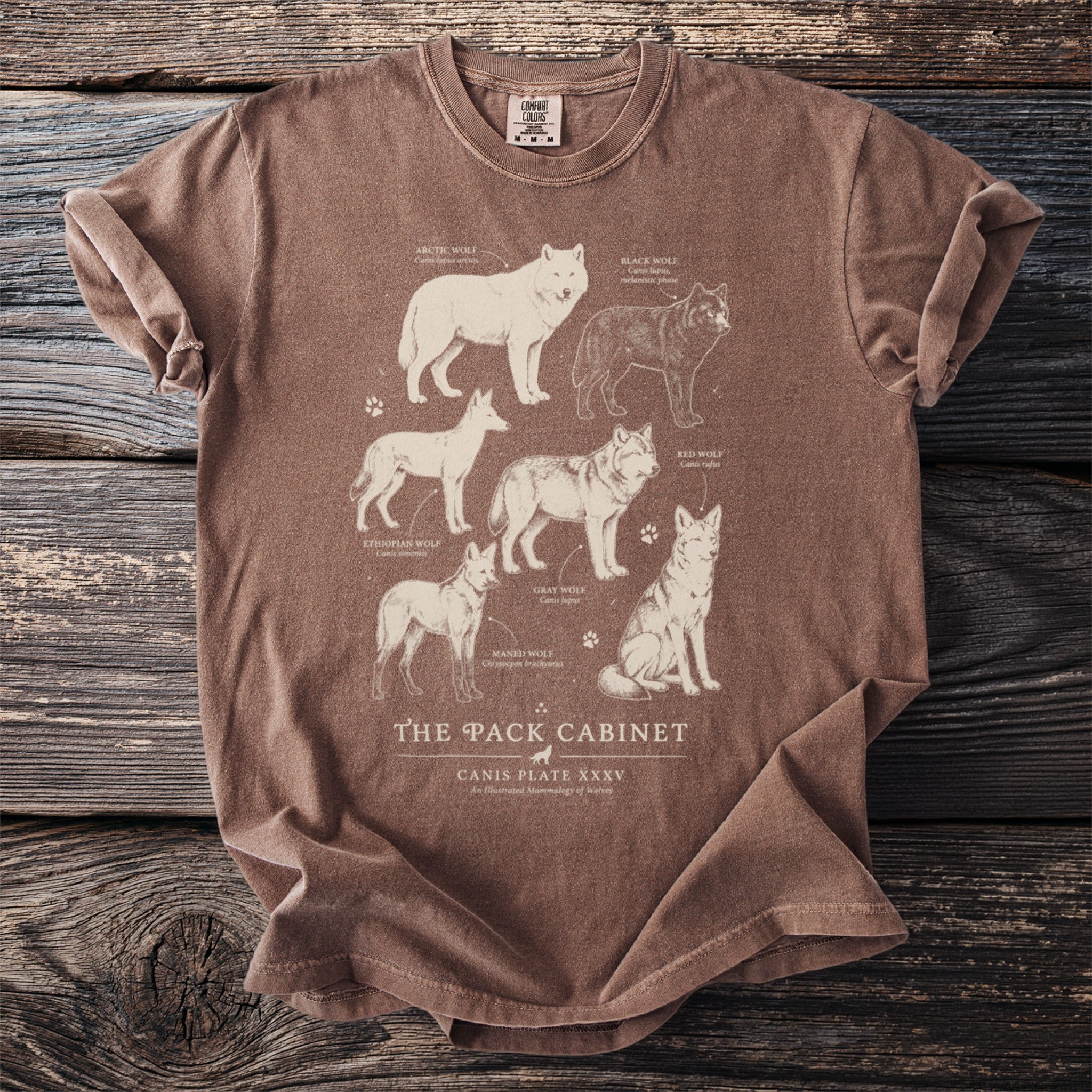 Brown t-shirt featuring illustrations of different wolf species and "The Pack Cabinet" text.