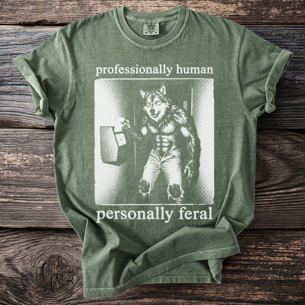 Olive green t-shirt with wolf graphic and text "professionally human personally feral".