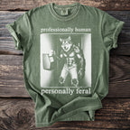 Olive green t-shirt with wolf graphic and text "professionally human personally feral".