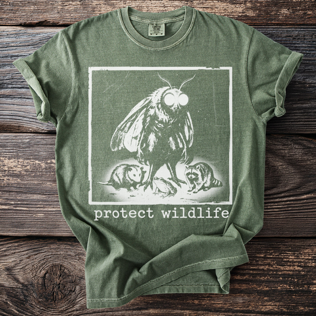 Green t-shirt with a moth, opossum, frog, and raccoon graphic and "protect wildlife" text.