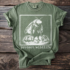 Green t-shirt with a moth, opossum, frog, and raccoon graphic and "protect wildlife" text.