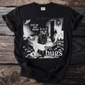 Black t-shirt with a cat on a bed surrounded by bugs and text saying "you're not alone there are bugs."