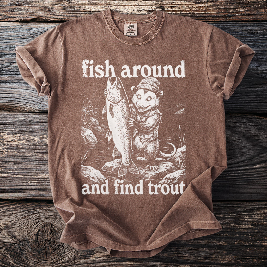Brown t-shirt with graphic of a possum holding a large trout, text "fish around and find trout".