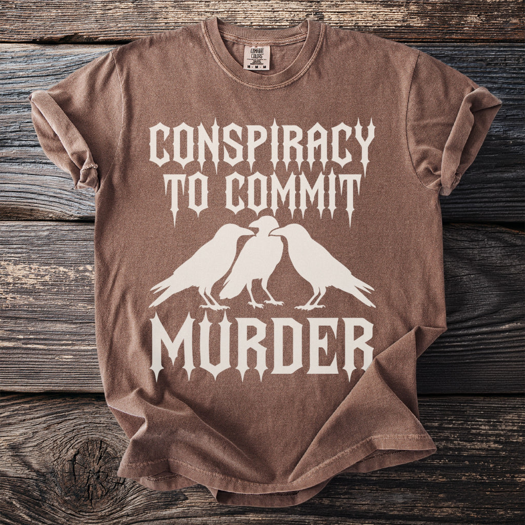 Brown t-shirt with white text and three ravens: "Conspiracy to Commit Murder".