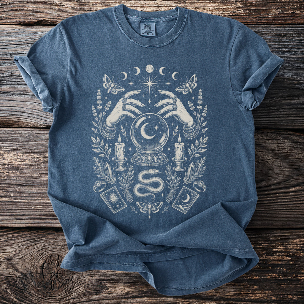 Blue t-shirt with occult design featuring hands, crystal ball, moon phases, and moths.