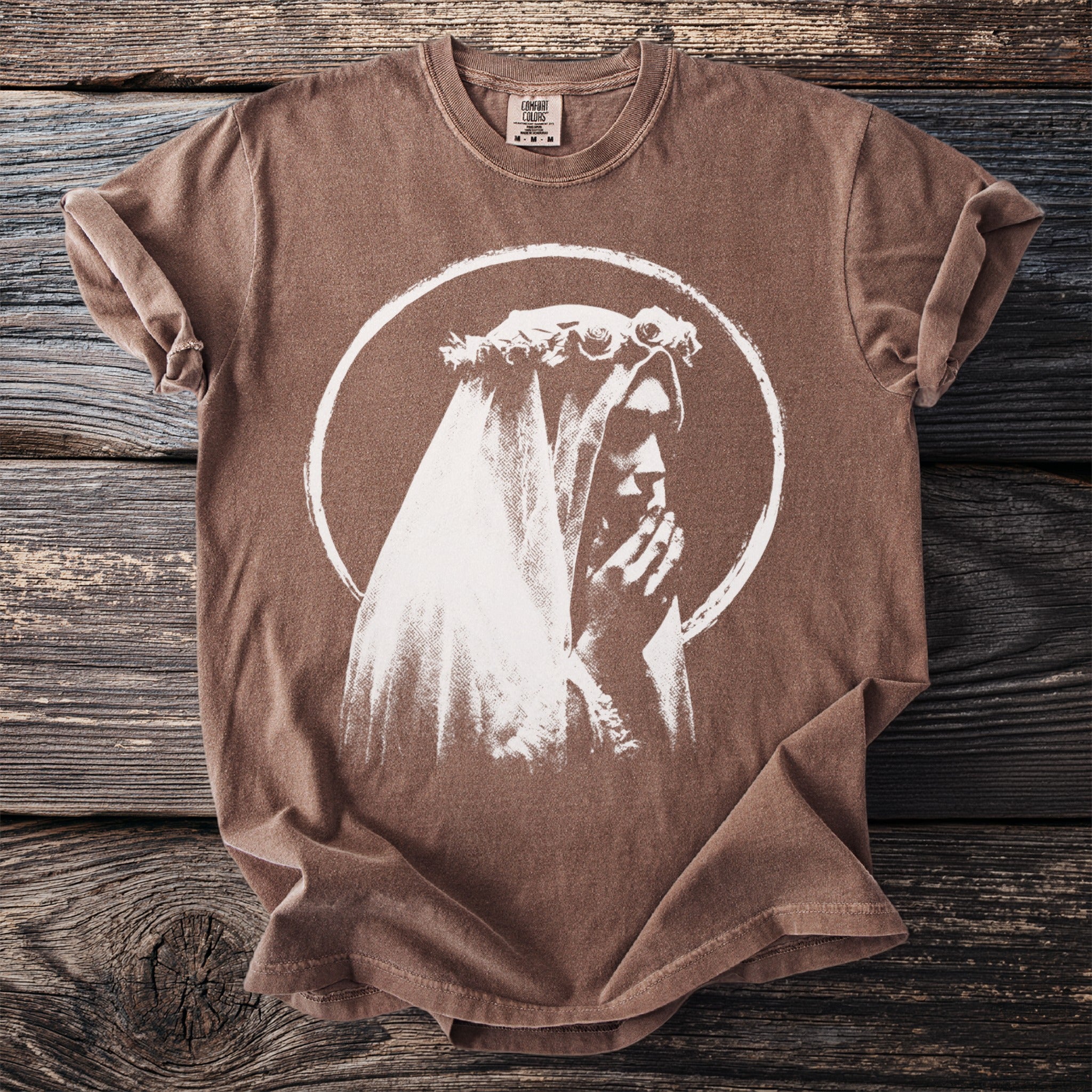 Brown t-shirt with white graphic of a figure wearing a veil and holding hands.