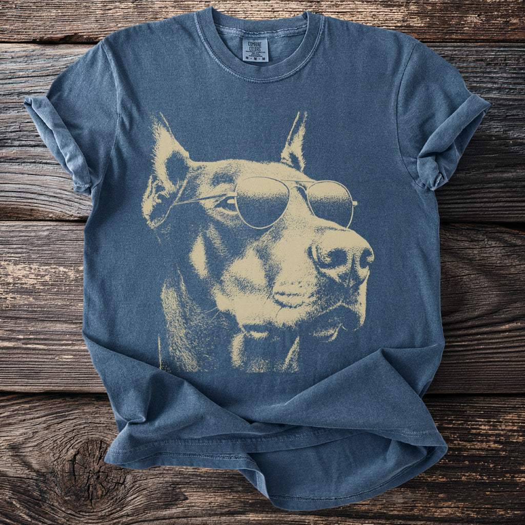 Blue t-shirt with a faded tan graphic of a doberman wearing sunglasses.