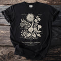 Black t-shirt with line drawing of night-blooming plants labeled "The Midnight Garden".
