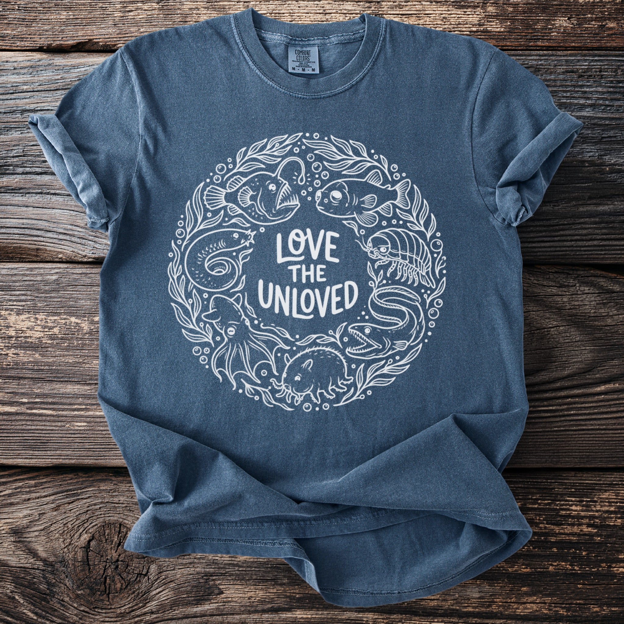 Blue t-shirt with white circular graphic of sea creatures and text "Love the Unloved".