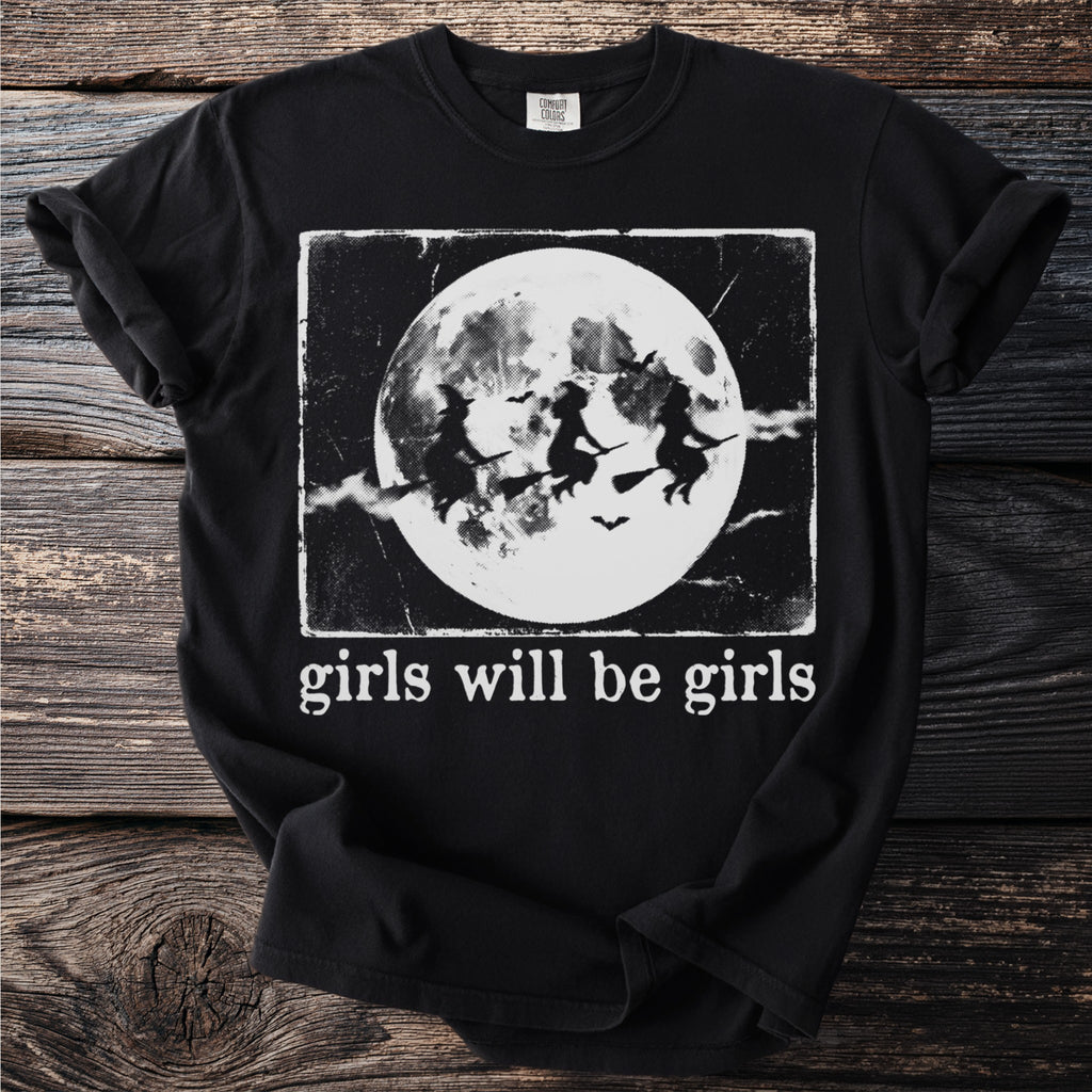 Black t-shirt with flying witches and "girls will be girls" text.