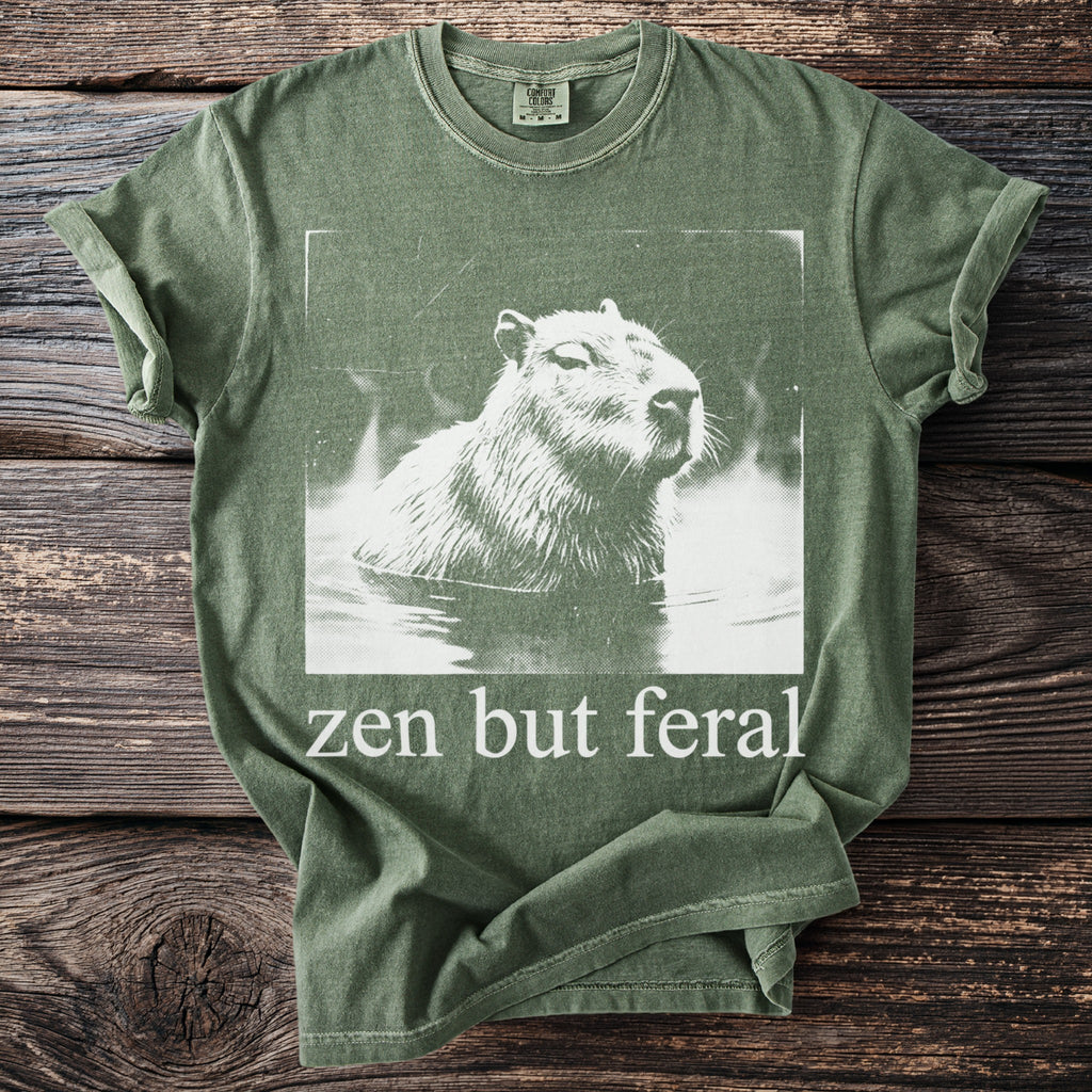 Green t-shirt with white capybara graphic and text "zen but feral".