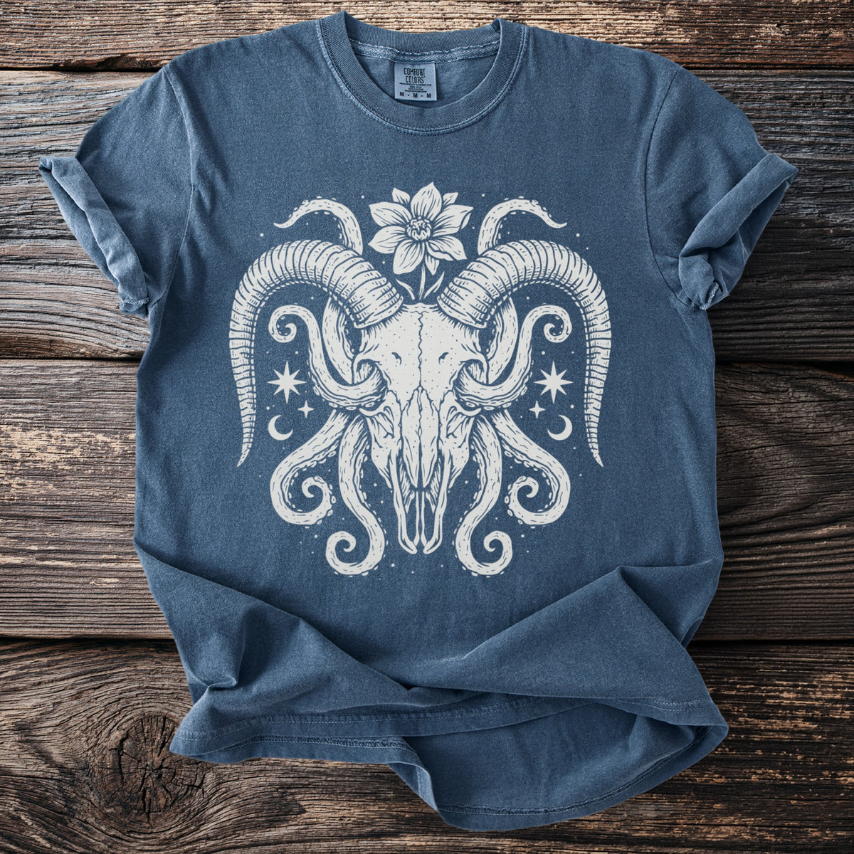 Blue t-shirt with white graphic of a ram skull, tentacles, flower, and stars.