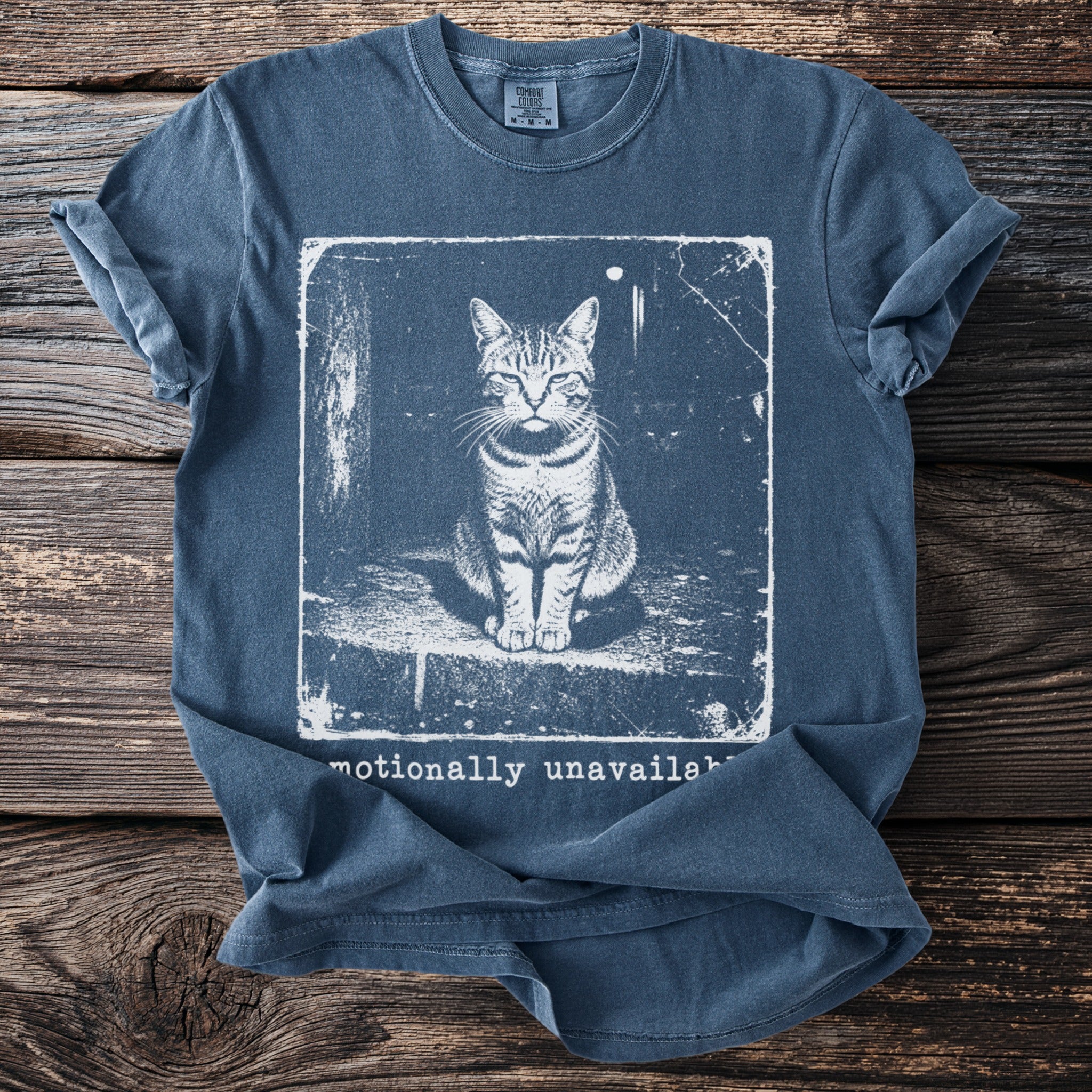 Blue t-shirt with a distressed print of a cat and text "emotionally unavailable".