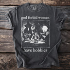 Dark t-shirt with graphic and text "god forbid women have hobbies."
