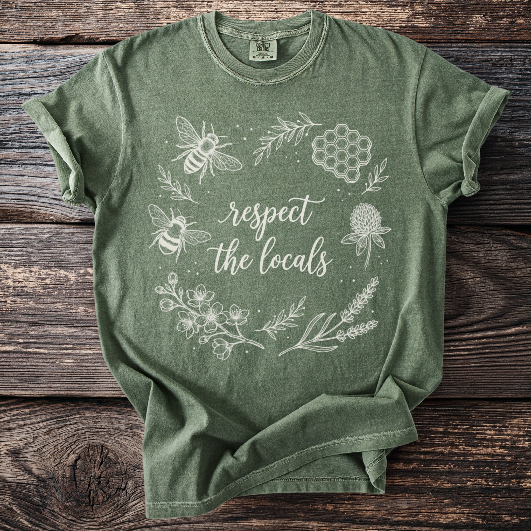 Green t-shirt with white line drawing of bees, honeycomb, and flowers with text "respect the locals".