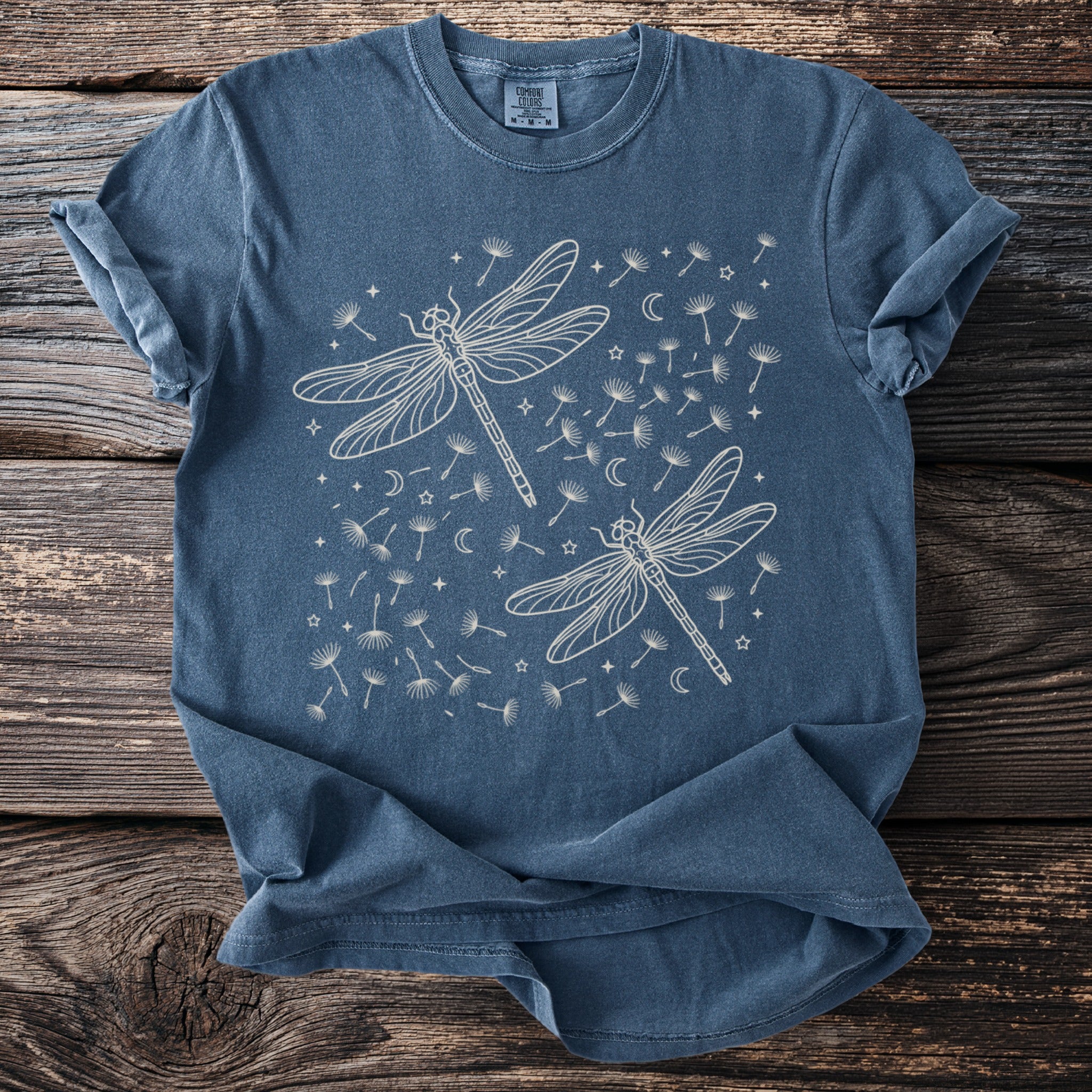Blue t-shirt with cream line art of two dragonflies and scattered dandelions.
