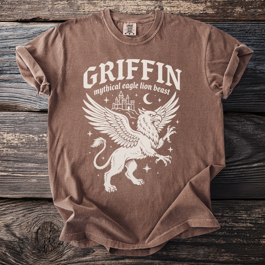 Brown t-shirt with white graphic of a griffin, castle, moon, and stars.