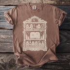Brown t-shirt with a cream graphic of an occult shelf filled with jars, a skull, and a spellbook.