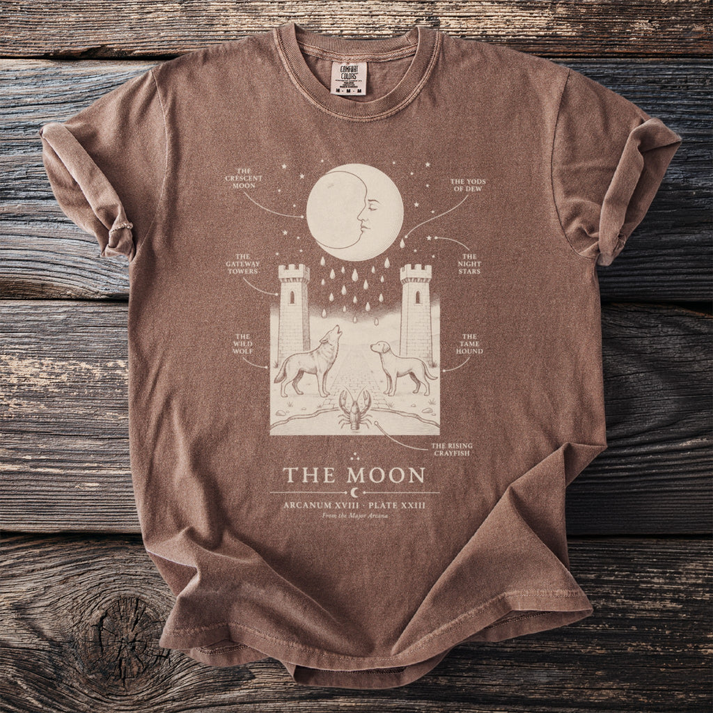 Brown t-shirt with "The Moon" design featuring crescent moon, towers, wolf, dog, and crayfish.